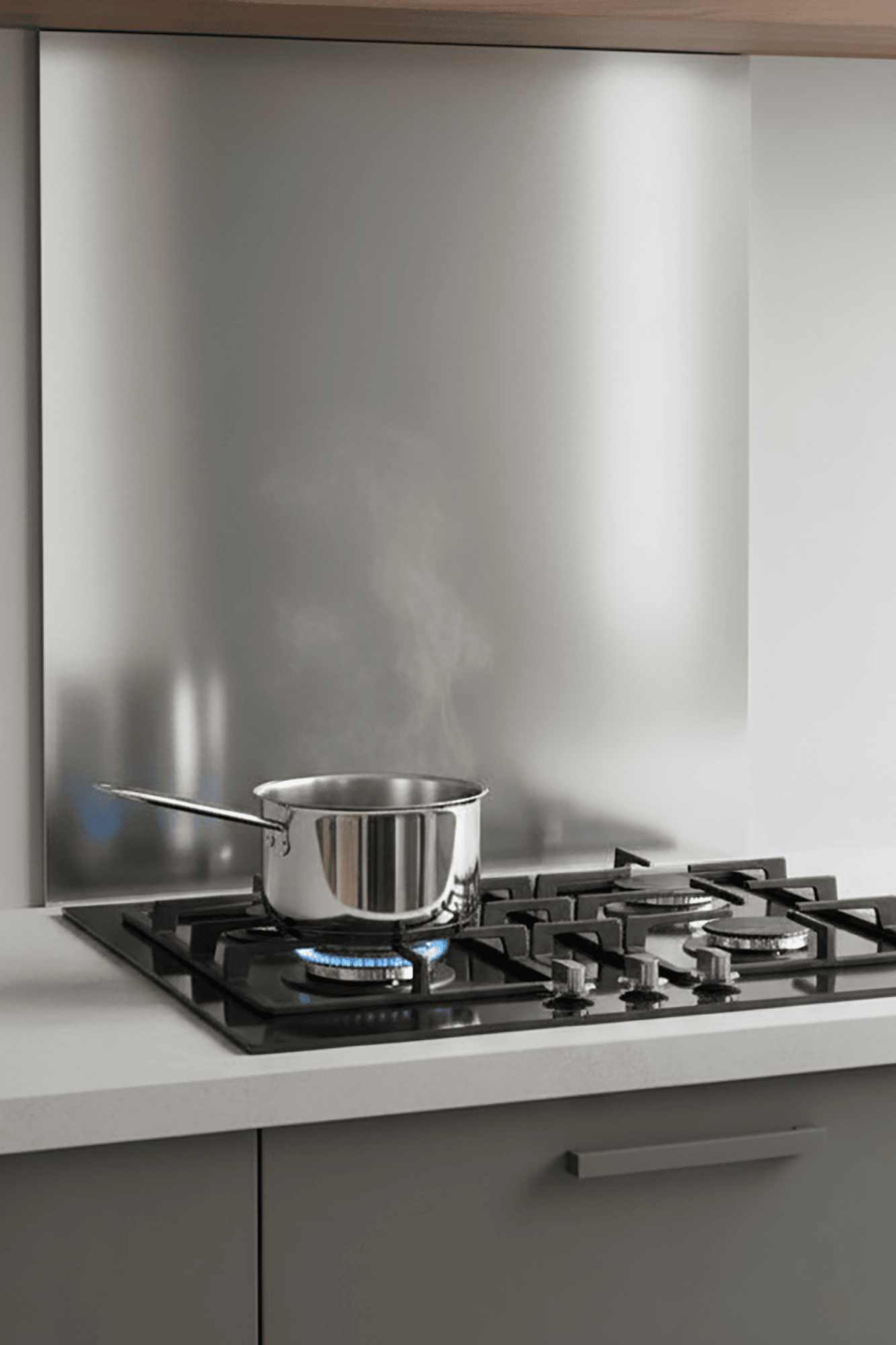 Casserole en acier inoxydable bouillante sur une cuisinière à gaz moderne, reflet sur crédence. John Steel.