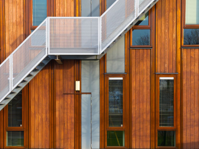 Escalier métallique sur façade en bois moderne avec fenêtres verticales, design architectural élégant. John Steel.